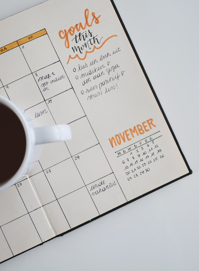 Goals written in a monthly planner beside a cup of coffee